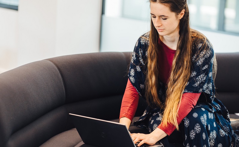 A student sits typing on a laptop.
