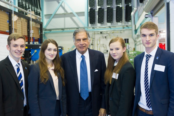 Four students in navy blazers smile to the camera with Mr Ratan Tata