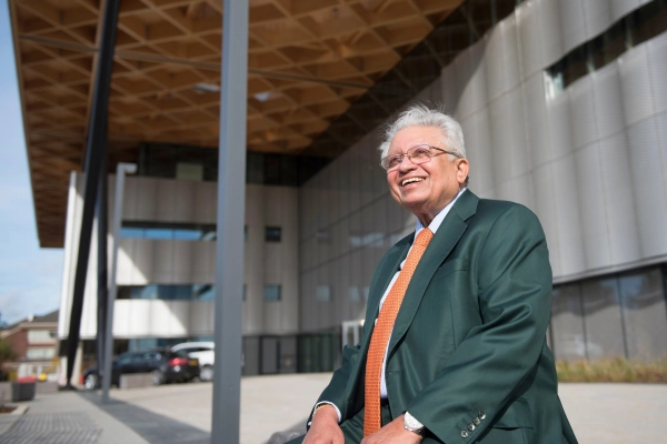 Lord Bhattacharyya smiles in the sunshine outside a building on campus