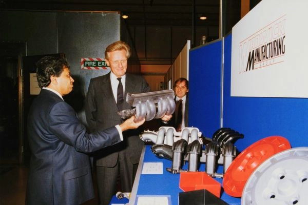 A person presents a large metal screw-like structure as part of a manufacturing demonstration.