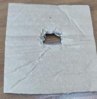 A piece of cardboard with a small hole cut in the middle of it.