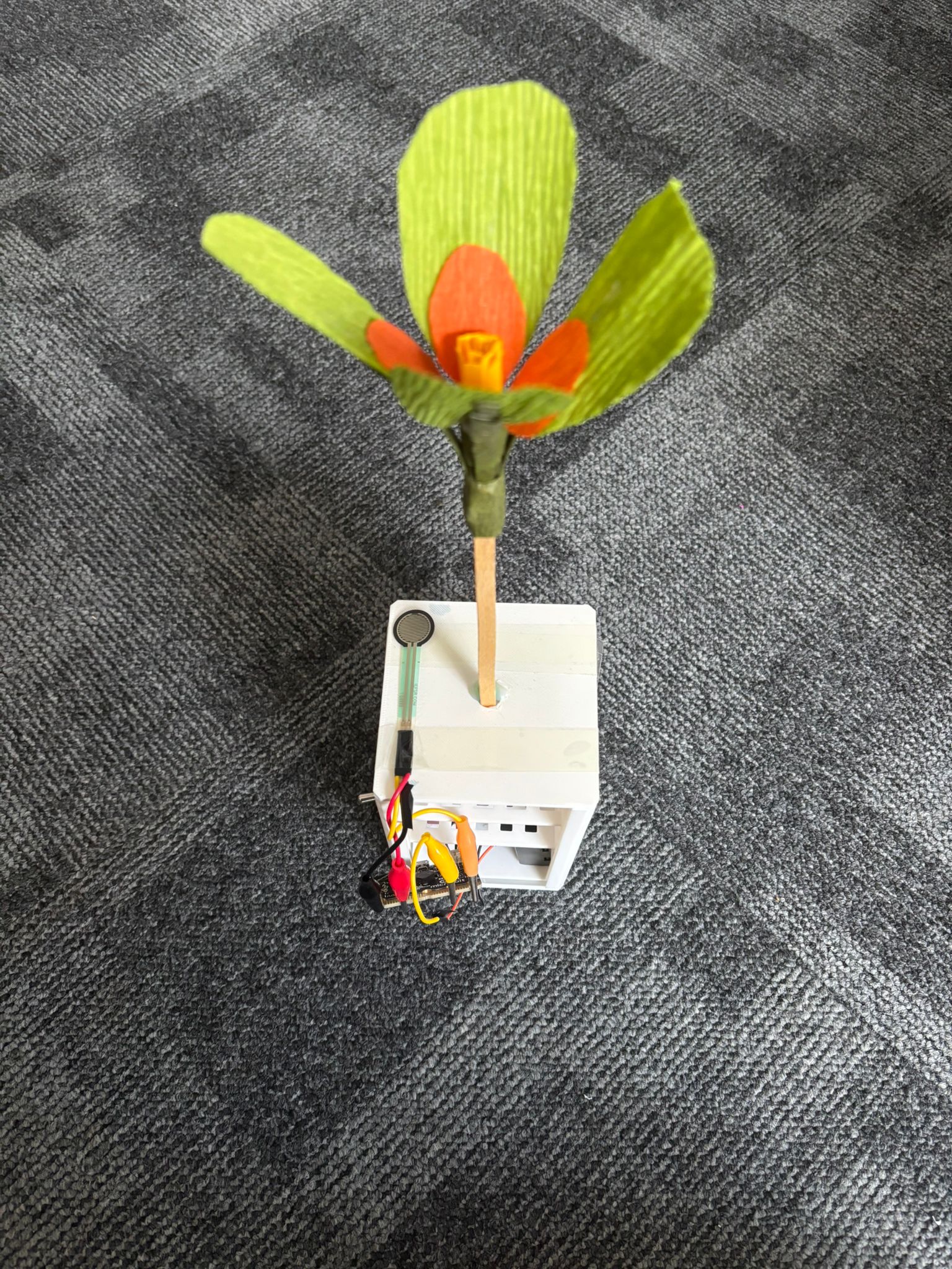 A paper flower mechanism inside a box with a sensor on the top