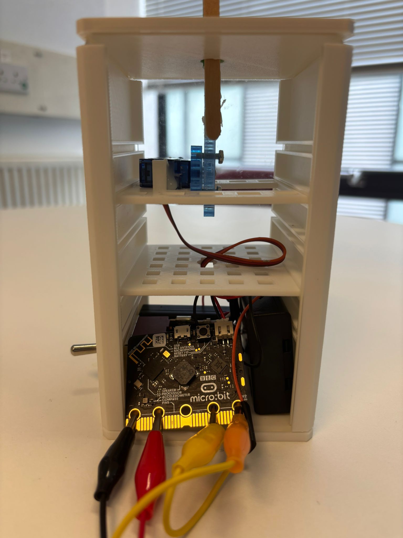 A microbit with wires connecting the pins to the motor in the paper flower mechanism