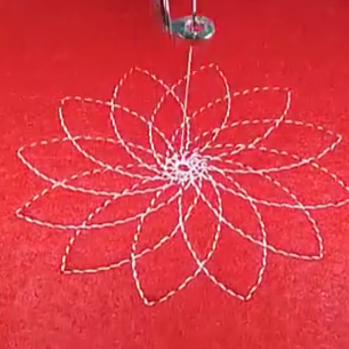 a flower pattern with petals radiating from the centre, stitched onto red felt with white stitching