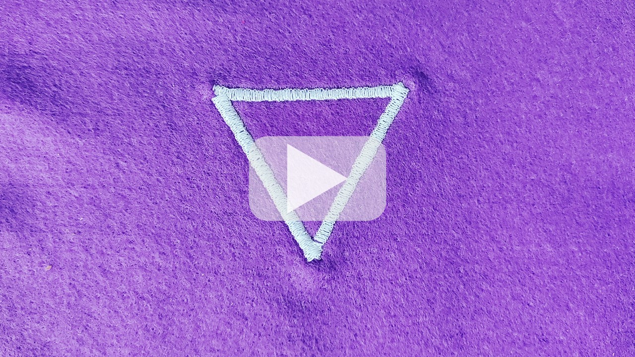 A triangle stitched in satin stitch, using white thread on a purple felt background.