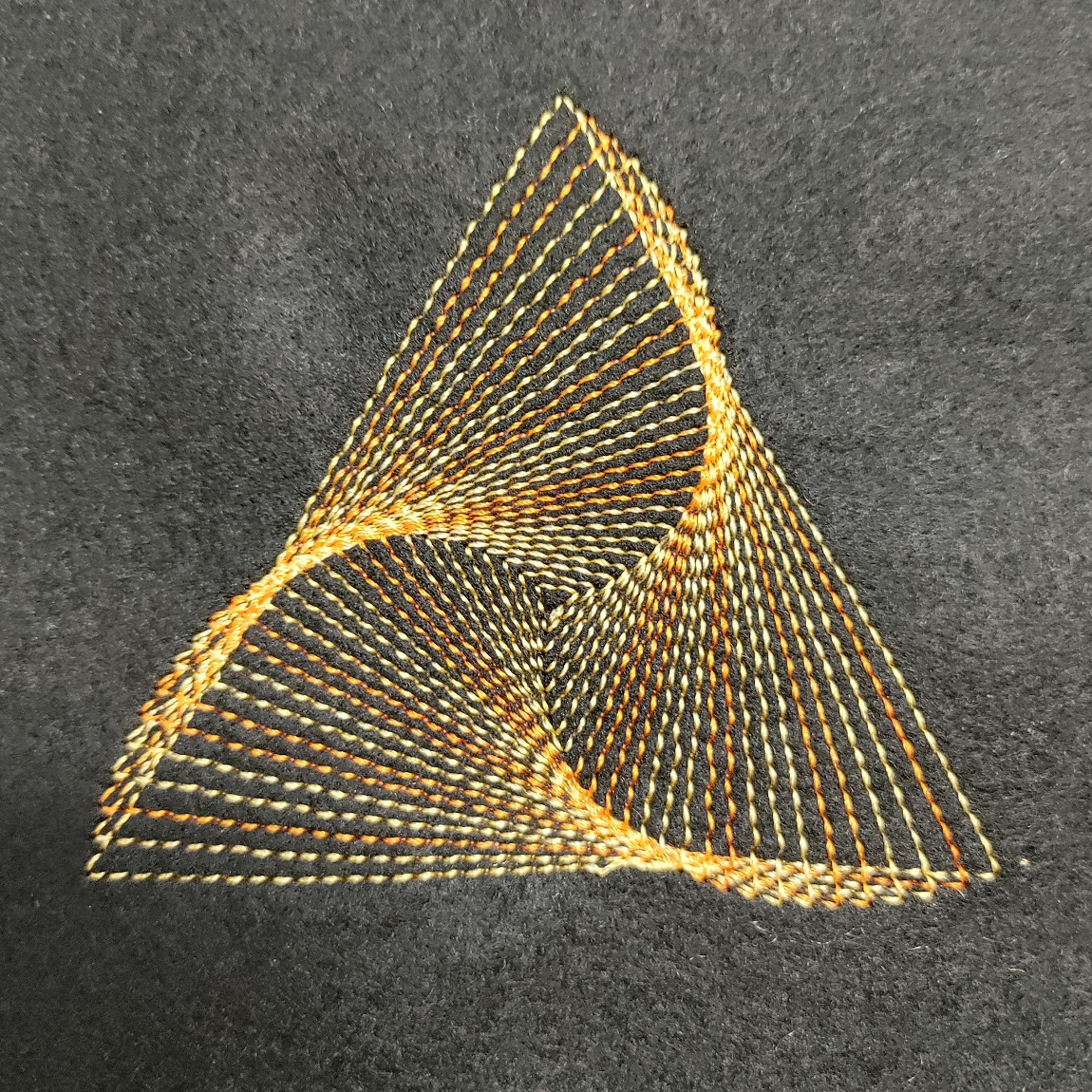 Its a series of triangles getting smaller and rotating slightly to give a swirl effect.  The pattern is stitched with yellow thread on a black background.