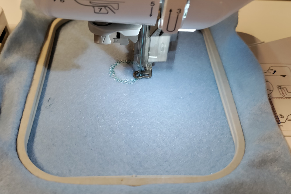 The embroidery machine stitching a designed pattern from code into felt.