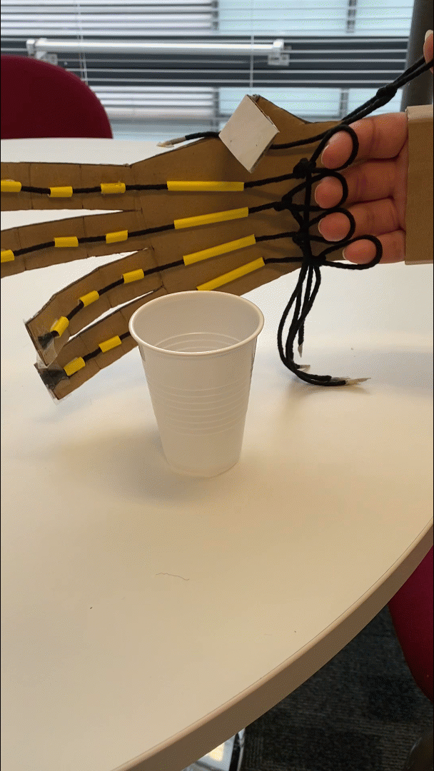 The robot arm is lifting up the plastic cup