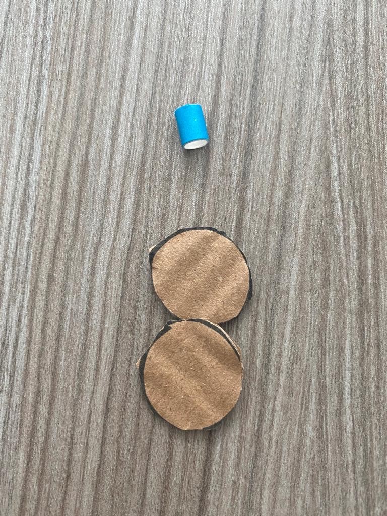 Two circles cut out of cardboard with radius 1cm. Next to them is a small length section of straw of length 1cm.