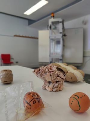 Two eggs with decorations of faces are in front of a machine called Eggdrop tower