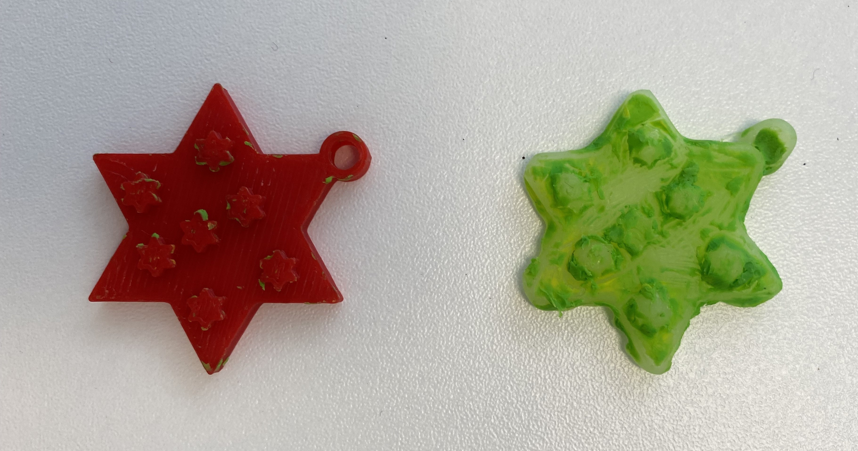 3d printed red flat star next to star made from the mould out of glue