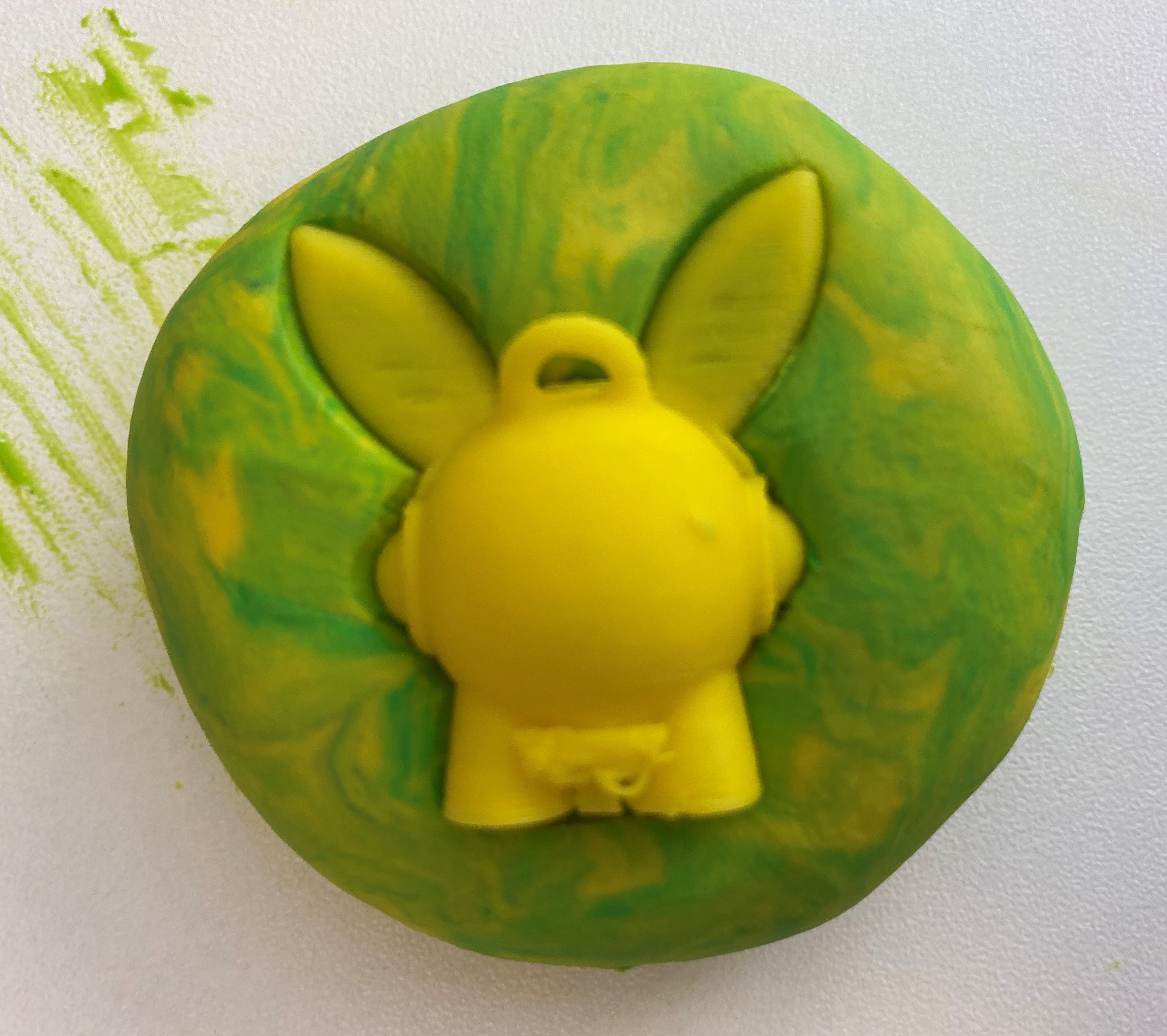 Top half of the rabbit 3d printed toy pushed into the green ball of playdough