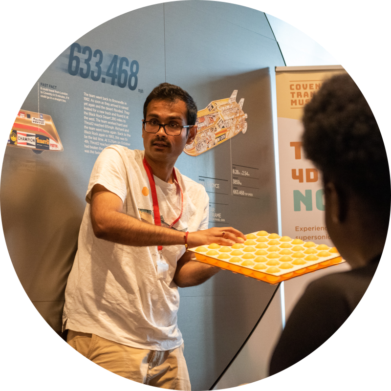 ishwar holds two sheets of wood with ping pong balls between them that represent the positions of atoms in a crystal structure