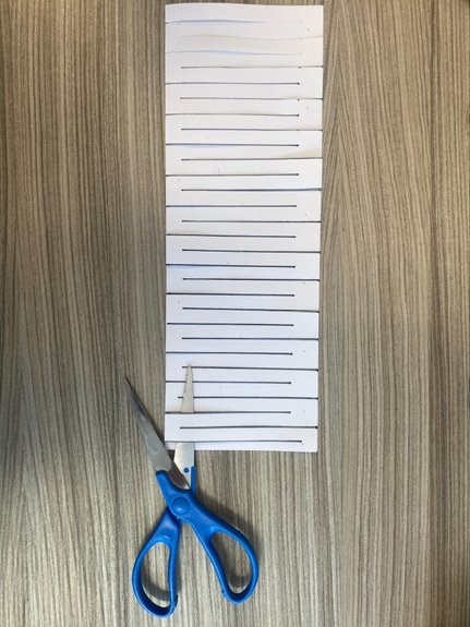a4 paper folded in half lengthwise with alternating lines and scissors at the bottom 