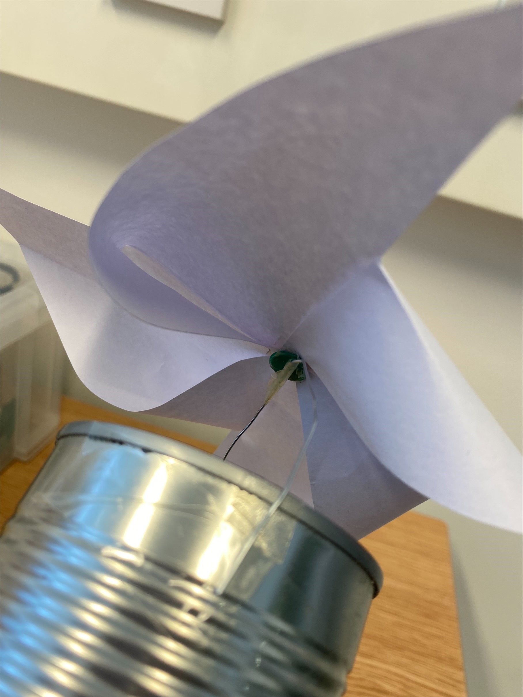 Tin can with a paper clip across the top and a paper windmill attached on top