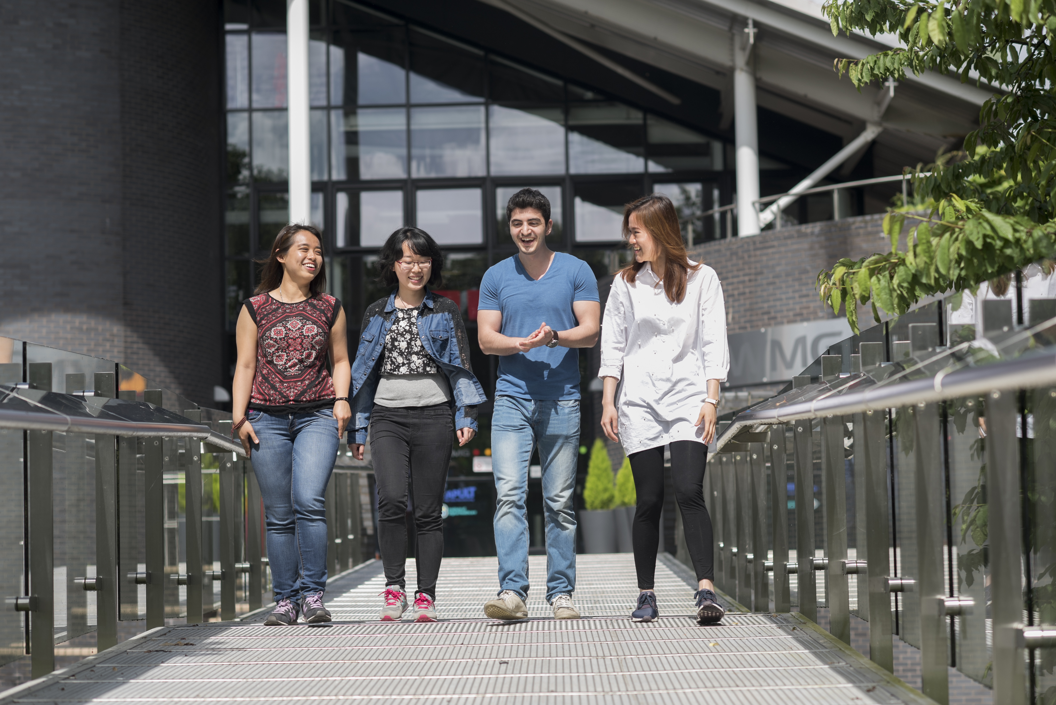 A group of WMG students cross the bridge outside a WMG building