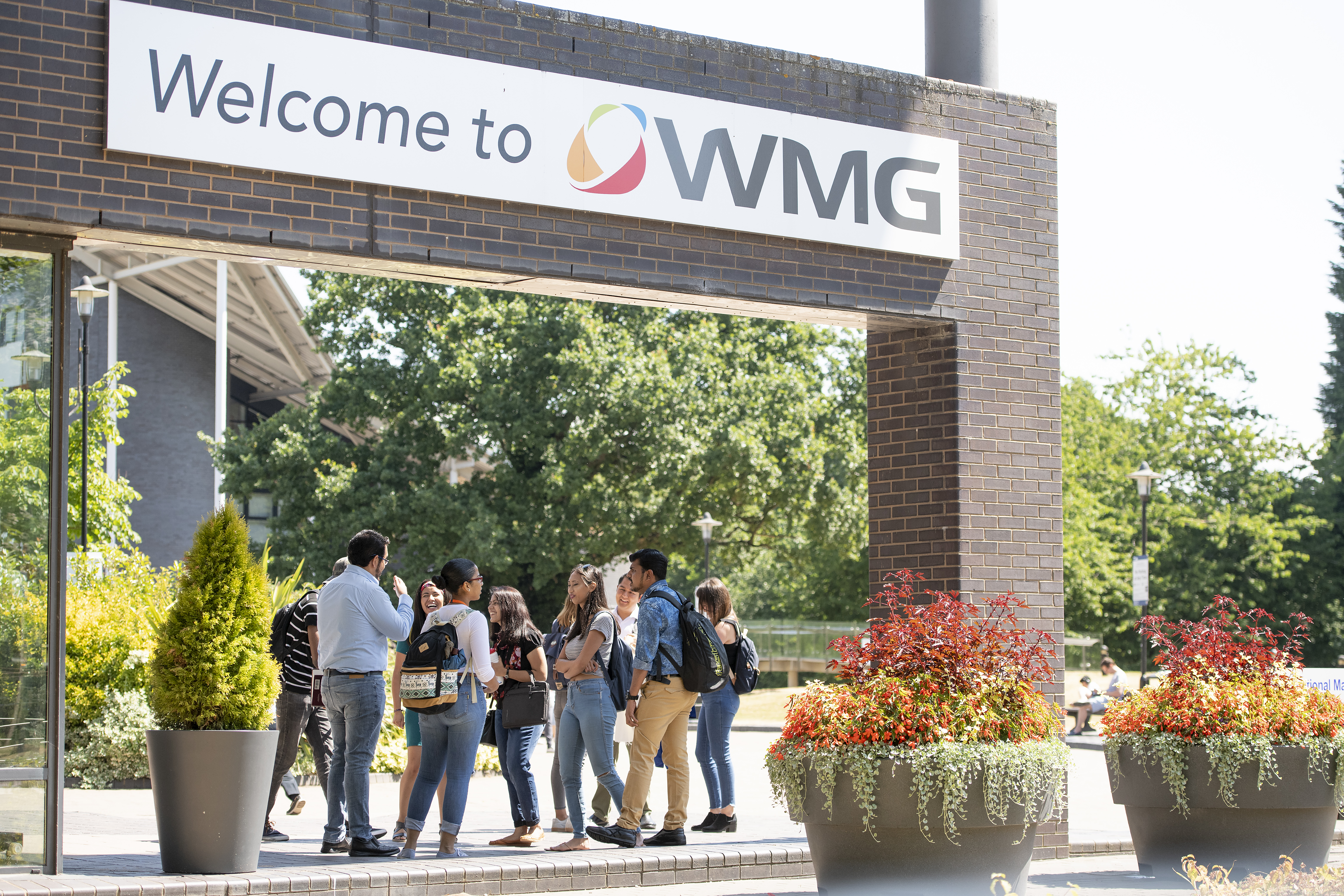 A group of WMG students standing outside a building with WMG sign