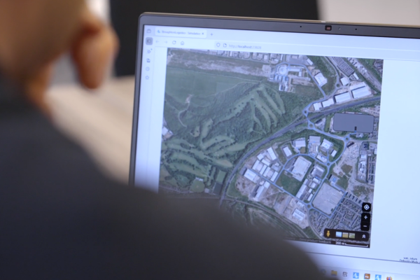 Over the shoulder shot of a man looking at a satellite image of a factory 