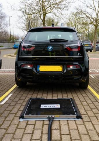 Electric vehicle parked in front of a charging plate.