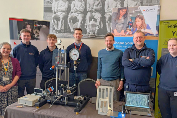 A group of people from WMG smile to camera behind a stand at the Warwickshire Skills Show.