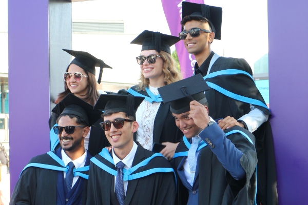 Students smiling in their graduation robes and mortar boards. 