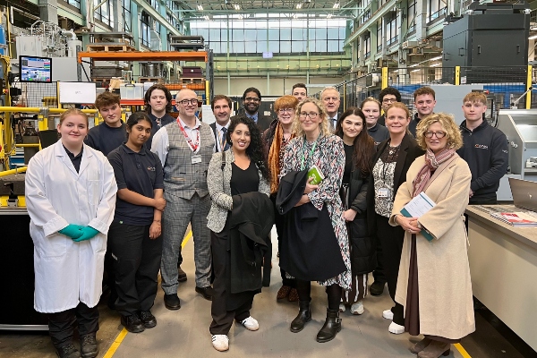 Group of people smiling to camera while visiting WMG's Engineering Hall. 