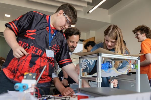 Two secondary school students work on an engineering project with a member of WMG staff