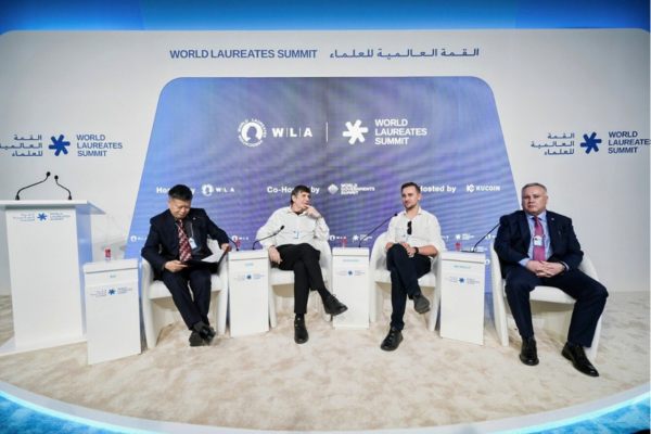 Four men sit on stage as part of a panel discussion at the World Laureate Summit
