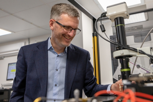 Person wearing a suit and glasses smiles while working in a laboratory