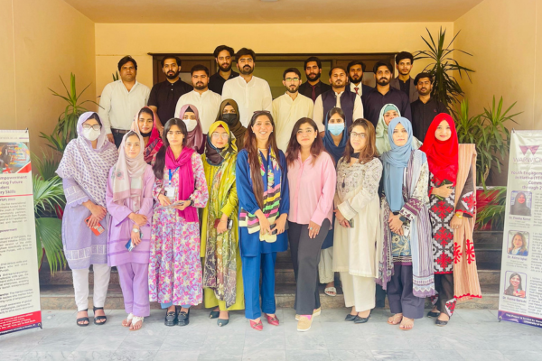 Group of young people in Pakistan with banners for the Youth Engagement and Empowerment Initiative around them