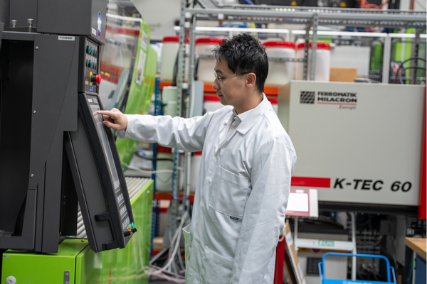 Dr Zhang uses a laboratory machine whilst wearing a white lab coat.