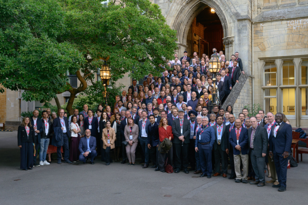 Large group of conference attendees stand outside historic Oxford building
