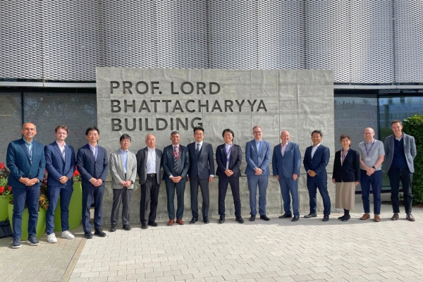 A group of people in smart dress stand outside the Professor Lord Bhattacharyya Building