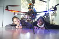 Abinaya Muraleeharan and Isha Patel, both 11, from Joseph Cash Primary School, Coventry, looking at an unmanned aerial inspection vehicle created by WMG