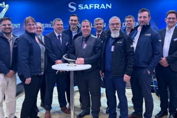 A group of people smiling to camera with an award against a blue, Safran-branded backdrop. 