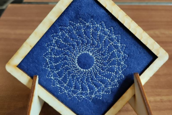 White geometric pattern embroidered onto blue felt
