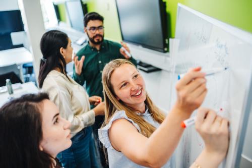 Female students writing on a whiteboard 