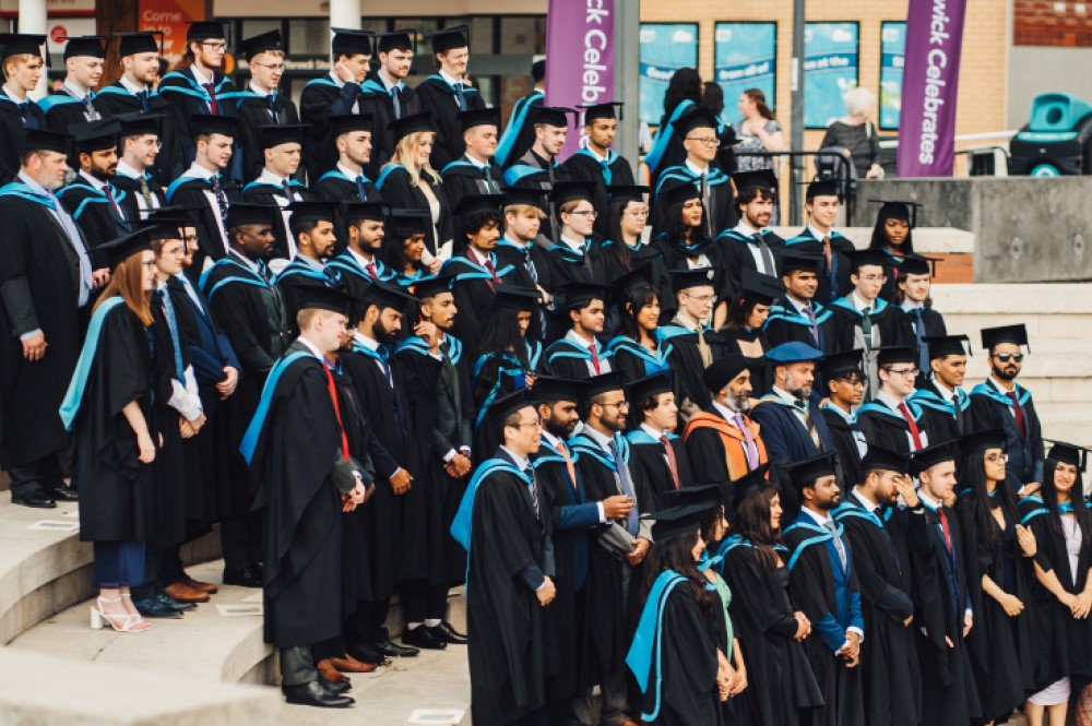 BSc Cyber Security graduates in their cap and gowns on the Piazza steps having their cohort photo taken