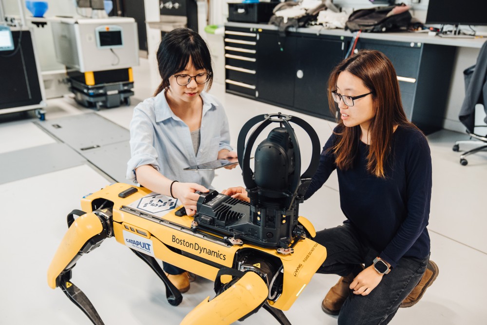 Two students interacting with a robot dog