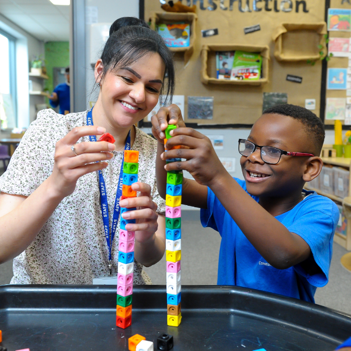 A smiling teacher and a smiling student working together