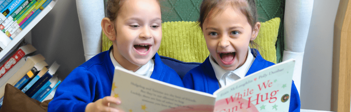 two young girls reading a story book happily together