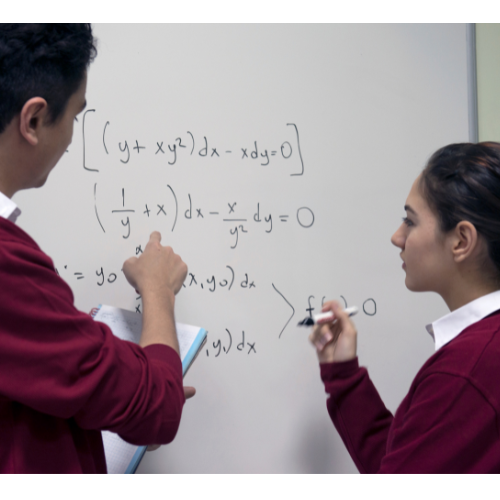 Two children writing maths equations on a whiteboard.