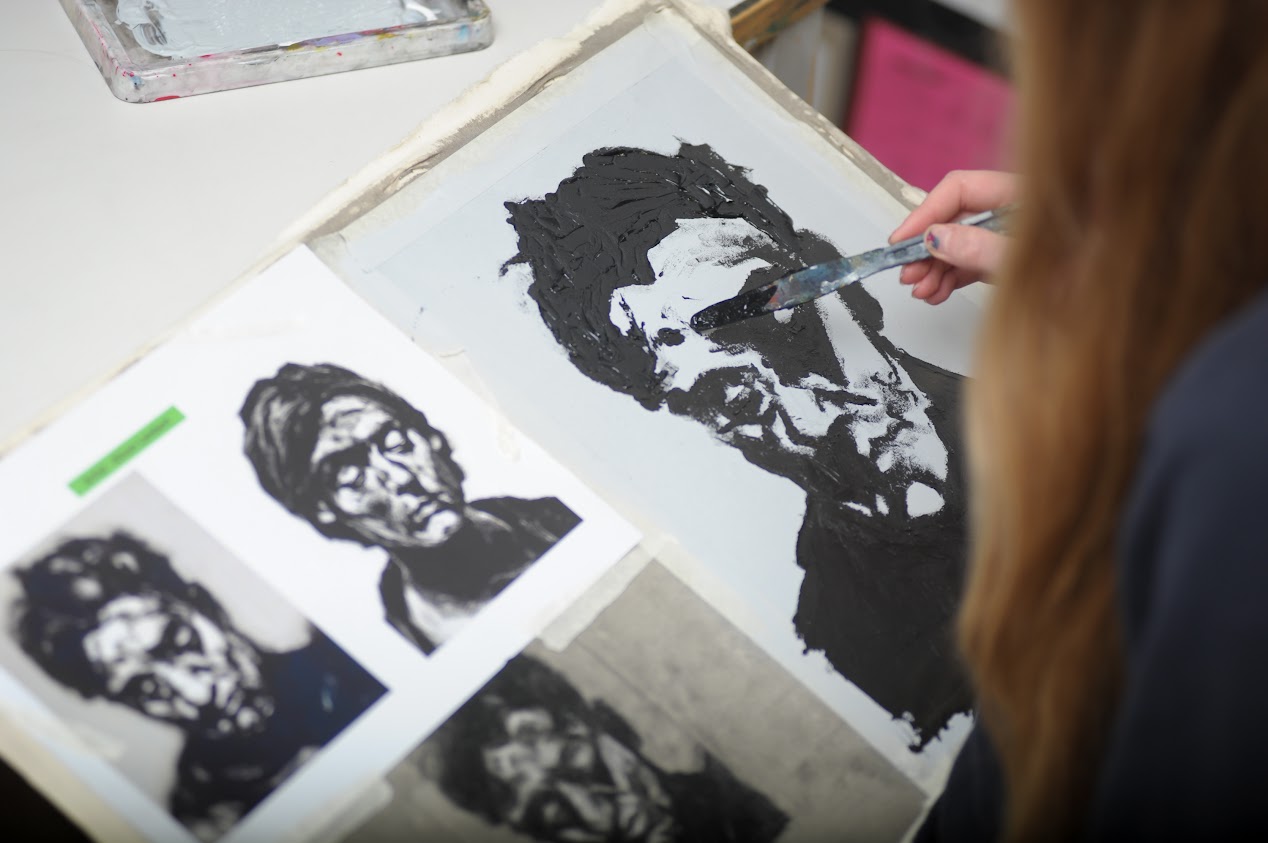 a student holding a painting brush working on a few ink portrait