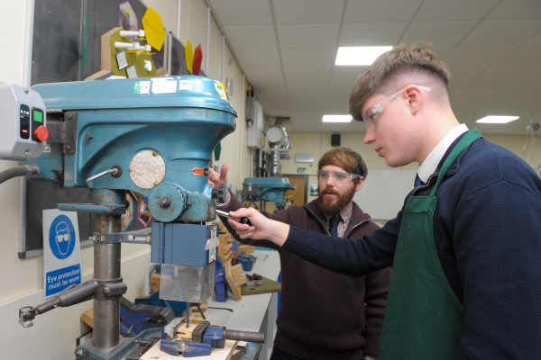 design and tech student and teacher operating a machine