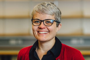 Carol Wild photo - woman wearing glasses and a red cardigan smiling