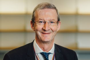 Des Hewitt photo - man with grey hair and glasses smiling