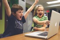 Pleased children cheering in front of a computer