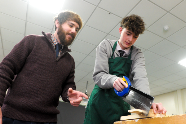 Teacher and student in a design class sawing a plank