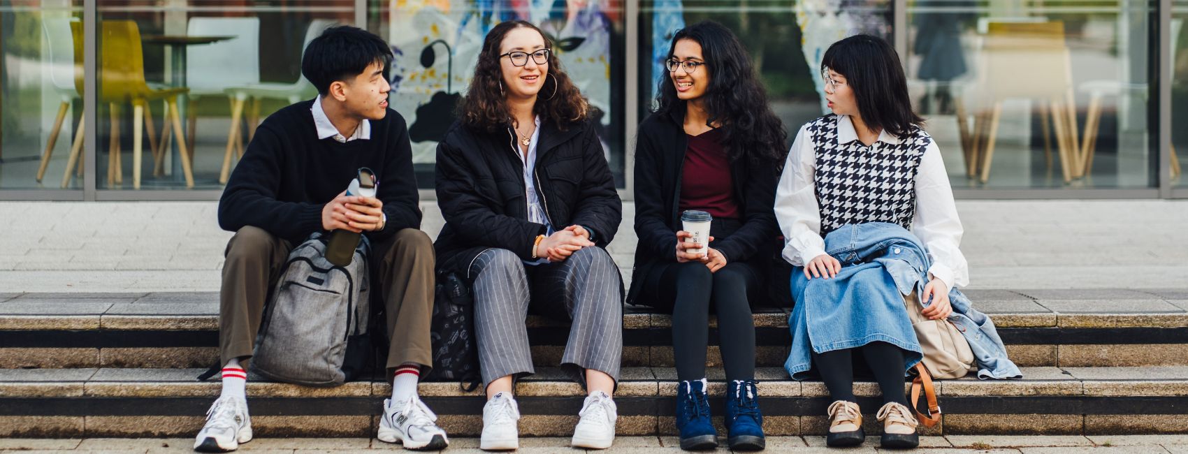 group of students conversing and sitting on a step