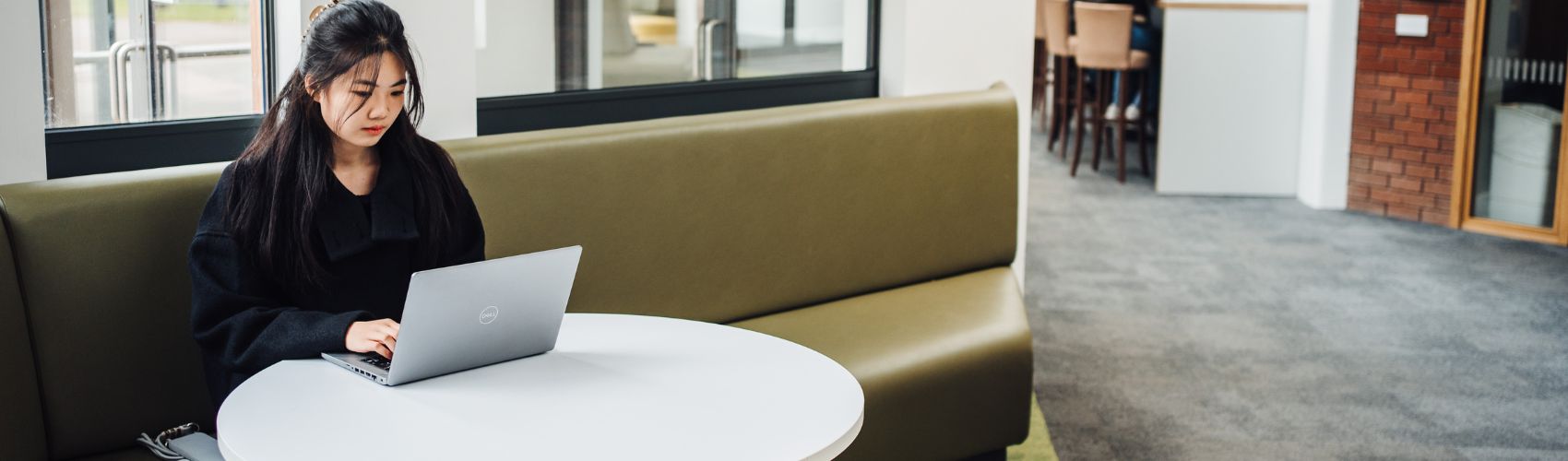 a female sitting at a desk whilst looking at a computer